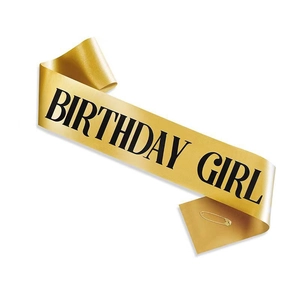 Close-up of golden Birthday Girl sash with black lettering and a safety pin fastening