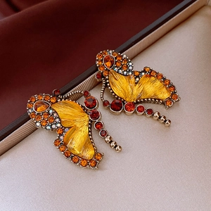 Detail of amber glass butterfly earrings with orange rhinestones and vintage gold trim