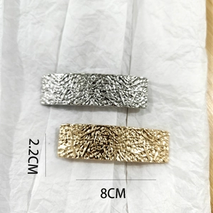Detail showing gold and silver rectangular metal hair clips with textured finish, 8cm size