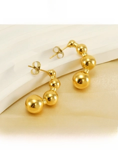 Macro detail of 18k gold plated titanium steel pea-shaped C-stud earrings on silk