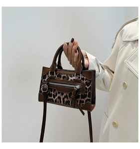 Detalle de la textura de leopardo y cremallera metálica en el bolso de cuero marrón