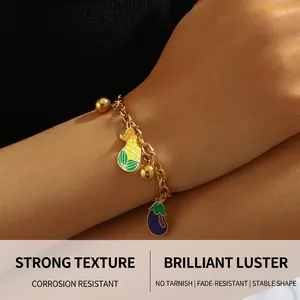 Detail of a gold chain bracelet featuring colorful enamel fruit and vegetable charms