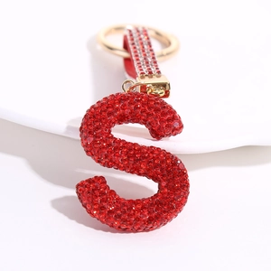 Sparkling red crystal letter S keychain with gold ring on a white minimalist base