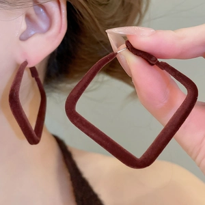 Détail de boucles d'oreilles carrées en velours marron foncé portées par un mannequin