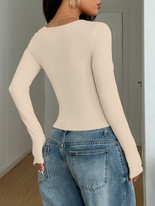 Rear view of a tight beige long-sleeve T-shirt in Y2K style paired with blue jeans