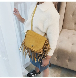 Detail shot of yellow faux suede girls crossbody bag with long fringes and metal buckle