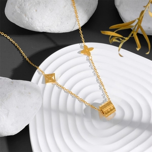 Detailed close-up of gold stainless steel necklace with cylindrical carved pendants