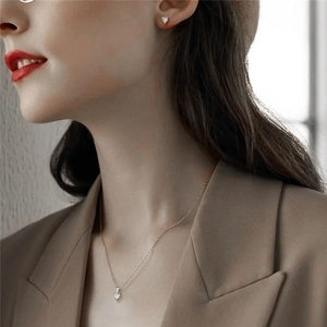Close-up of elegant S925 sterling silver heart-shaped necklace and earrings set on model