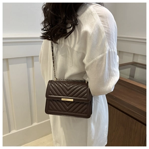 Model view of brown quilted shoulder bag with gold chain strap and elegant metallic buckle