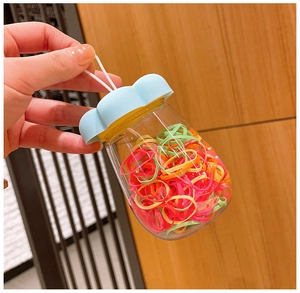 Mini plastic jar with colorful elastic hair bands and a blue petal-shaped lid for kids