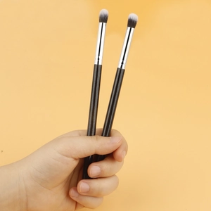 Detail of dual-ended eyeshadow brush with black handle and soft gradient synthetic bristles
