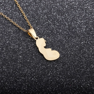 Close-up of gold pregnancy silhouette pendant with heart detail on a sparkling background