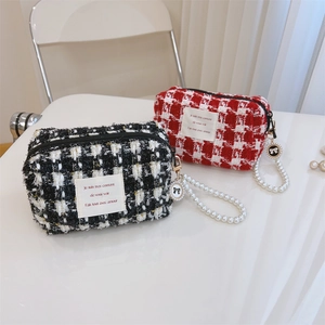 Macro view of woven tweed makeup bags with large pearl handles and bow pendants