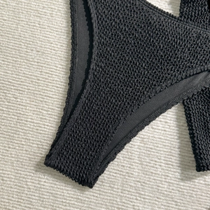 Detail shot of the black honeycomb textured smocked fabric for a three-piece bikini set