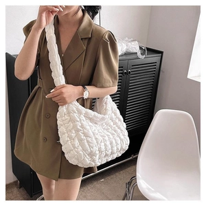 Close-up of white quilted puffer bag with wide strap and soft cloud-like texture