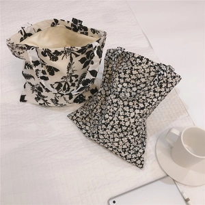 Flat lay of floral canvas tote bags on a quilted surface with lifestyle accessories
