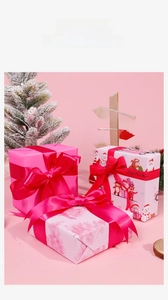 Pink Christmas gift wrapping paper rolls with festive deer patterns and satin ribbons