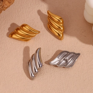 Macro view of geometric triple-layered wing stud earrings with polished gold and silver finish