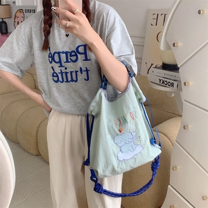 Detail of light green tote with elephant embroidery and blue rope knot shoulder strap