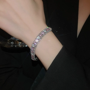 Detail of double-row pink and white zircon bracelet on wrist with elegant black outfit