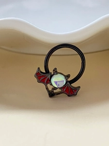 Detailansicht eines schwarzen Fledermaus-Piercingrings mit roten Flügeln und Opal
