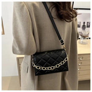 Detail shot of a black quilted crossbody bag with golden chain and leather strap