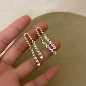 Close-up of French retro pearl dangle earrings with sparkling crystal accents held in hand