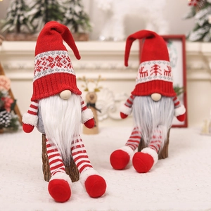 Detail of red and white Christmas gnomes with knitted hats on wooden logs in warm setting