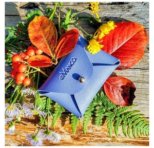 Blaue Leder-Schmucktasche mit silbernem Druckknopf auf rustikalem Holzgrund mit Blumen