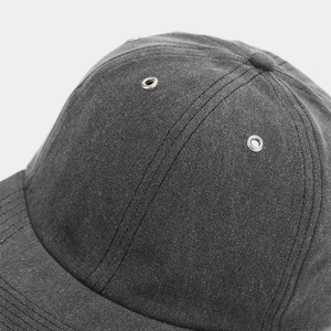 Detail of dark grey twill cotton baseball cap showing stitching and metal vent eyelets