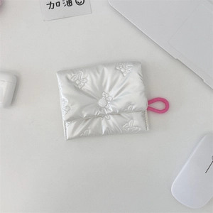 Macro shot of silver bow embossed mini storage bag with pink elastic lanyard on a desk