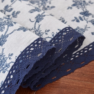 Close-up of retro floral linen table runner with navy blue lace edge detail
