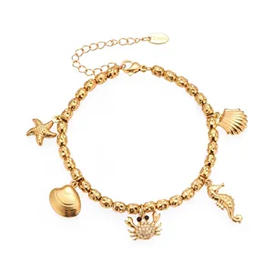 Detalle de pulsera de cuentas en acero dorado con dijes de estrella de mar y concha