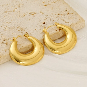 Polished gold-plated C-shaped chunky hoop earrings on a textured stone pedestal