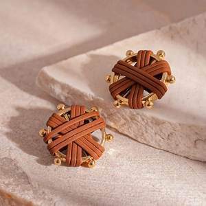Close-up of vintage golden round earrings with woven brown leather and metallic accents