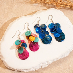 Détails de boucles d'oreilles géométriques en nacre colorée sur socle en pierre