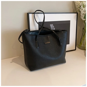 Detail of a black tote bag with grain texture and Fashion & Bags tag on a desk