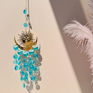 Detail of sun and moon crystal suncatcher with blue prisms and golden metal accents