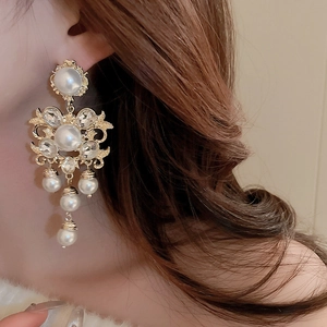 Detail of vintage palace style flower earrings with faux pearls and tassels on model