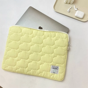 Detail view of yellow cloud-quilted laptop sleeve showing padding and premium texture