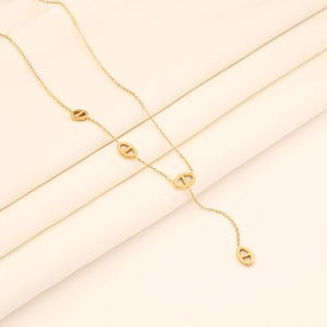 Detail of gold pig nose link necklace on soft beige fabric showing fine chain quality