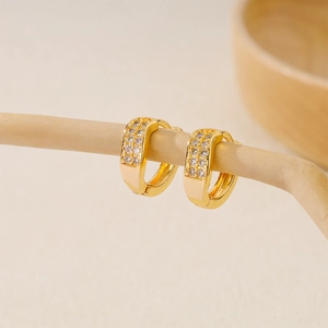 Detailed close-up of gold plated huggie earrings with double rows of clear cubic zirconia