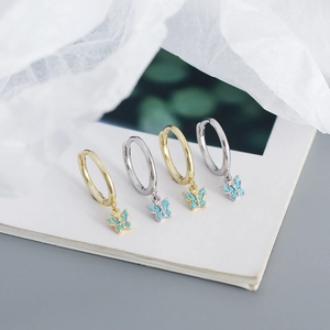 Close-up of gold and silver butterfly hoop earrings with turquoise stones on white