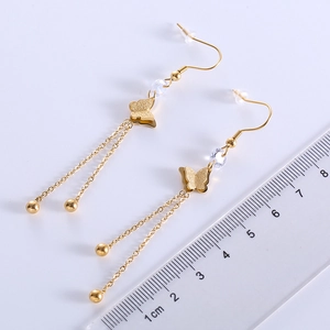 Golden butterfly drop earrings with beads and long tassels next to a measuring ruler
