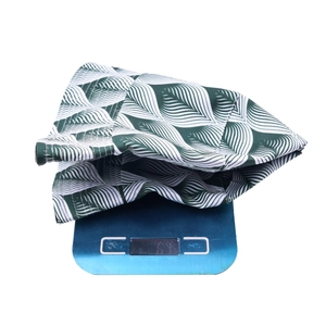 Detail shot of leaf print bucket hat weighing 67g on a blue scale for material density