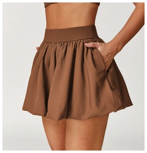 Detail of pleated brown tennis skirt featuring a wide elastic waistband and side pockets