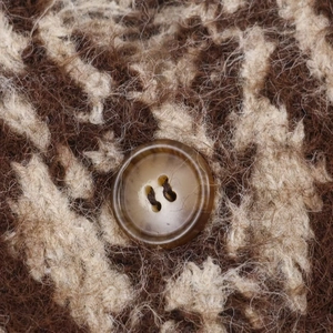 Dettaglio di un bottone in resina marrone su maglione jacquard con trama in lana soffice