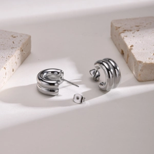Detail showing polished silver double-layered C-shape stainless steel earrings on stone