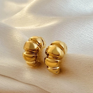 Detail of 18k gold croissant hoop earrings featuring twisted texture on silk fabric