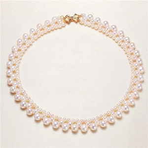 Detailed top view of double-layer woven white pearl necklace with gold bow clasp